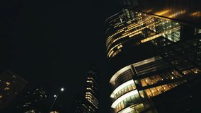 Low angle dolly shot illuminated skyscrapers cityscape at night, financial district looking up modern architecture office buildings, city business center downtown, gimbal shot, Warsaw evening street - Powered by Shutterstock - Get 15% off with code: PIKWIZARD15