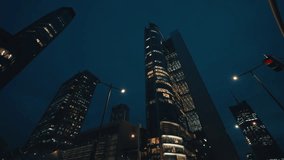 Low angle dolly shot illuminated skyscrapers cityscape at night, financial district looking up modern architecture office buildings, city business center downtown, gimbal shot, Warsaw evening street - Powered by Shutterstock - Get 15% off with code: PIKWIZARD15