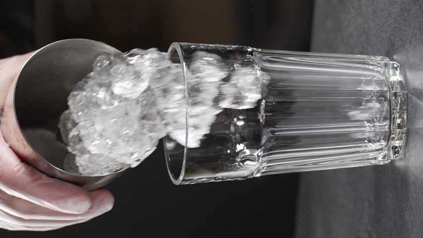 Bartender adds ice cubes into glass. slow motion, making cocktail at bar counter, Vertical footage. Black background. Full hd | Shutterstock HD Video #1111244103
