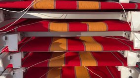 4K video with camera movement. Beach loungers with orange-yellow-red stripes on the fabric lie in stack. Concept of end of summer vacation, sea holiday, ocean tourism, travel, relax, resort, hotel