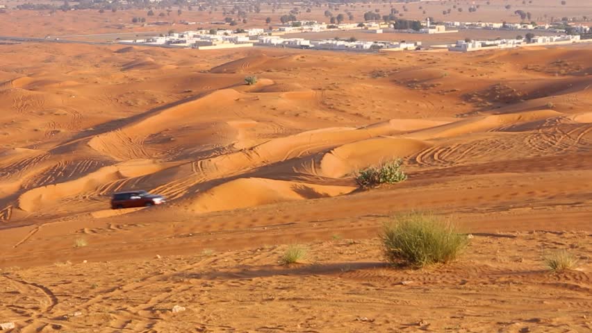 4x4 cars and quads dune bashing in Dubai, driving up the sand dune in the Fossil Rock desert with mountains in the background, Sharjah, United Arab Emirates.