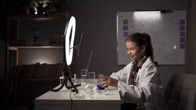 School girl making easy chemistry experiments and recording a video for followers, blogger teen in front of camera for vlog, make vlog for social media