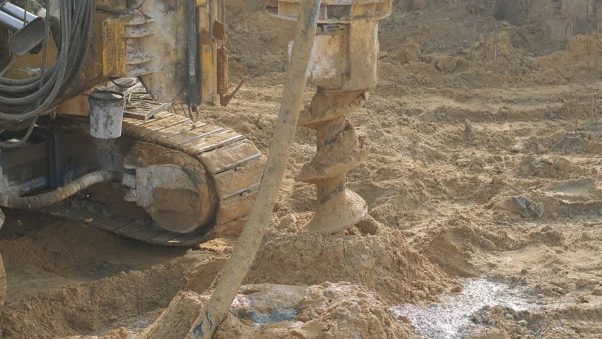 Equipment for installing piles in ground, heavy machines for driving pillars work in laying the foundation building. Construction aerial view height. Construction site drilling pile foundation. Royalty-Free Stock Footage #1111252247