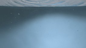 Mango falling into water in super slow motion with blue background. Mango hitting water surface
