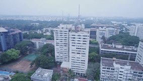 An aerial video showing the Anntana Tower over a skyscraper. Above, hazy views reveal a 360-degree rotating office complex and residential neighbourhoods. A view of a metro train track.