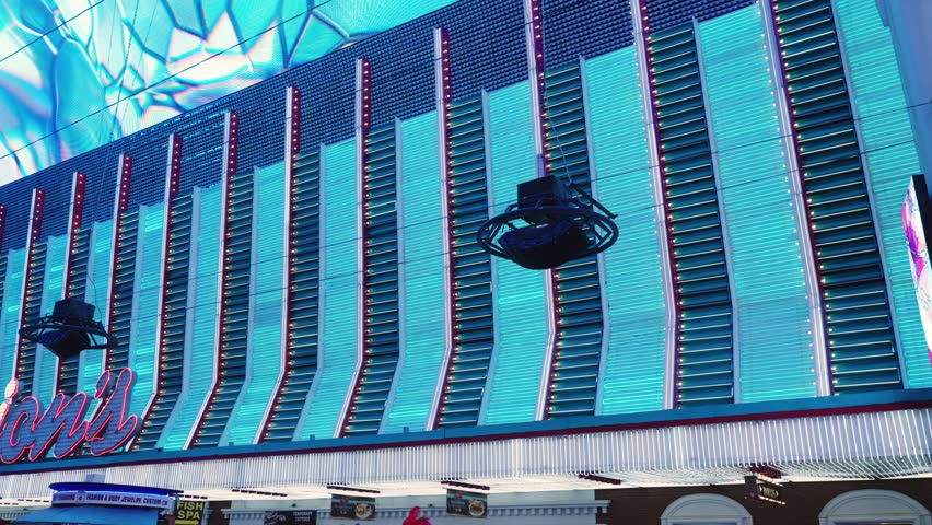 Blue neon LED lights in alternating blue and dark blue stripes channel down the side of a Las Vegas hotel casino in the old town Fremont district