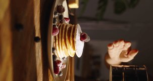 Female sprinkling sugar powder onto stack of pancakes. Advertising vertical video. Treat for eyes and taste bud. Leisurely cozy morning, essence of lifestyle, food, recipes, cooking, and domestic life