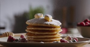 Sprinkles powdered sugar on perfect stack of pancakes, in kitchen scene. No people, advertisement. Kitchen-themed video, joy of healthy eating recipes for family, recipes for every day and weekends