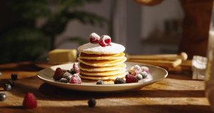 American traditional breakfast on kitchen background. Unknown sprinkles powdered sugar on pancake pancakes with berries. Advertising. Little celebration of taste for weekend morning. Gluten-free
