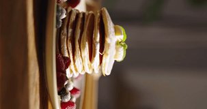 Pancake essence of American traditional breakfast. Mouthwatering pancake with blueberries, raspberries and sugar powder in morning light. Healthy eating gluten-free recipes. Vertical video, no people