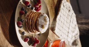 Sprinkling sugar powder on stack of delicious pancakes. Close-up shot beautiful arrangement of berries and powdered sugar on plate. Treat for eyes and taste buds. Vertical video. Gluten free food