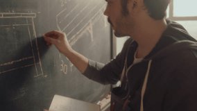 Professional carpenter looking at notes in copybook and drawing measurements for furniture drafts on chalkboard in a workshop - Powered by Shutterstock - Get 15% off with code: PIKWIZARD15