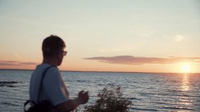 Young man tourist enjoying beautiful sunset, vacation, taking photo