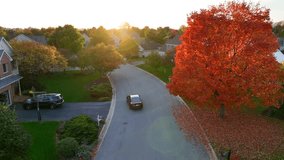 Black car driving through American neighborhood during autumn sunset. Aerial tracking shot among houses and colorful trees in the fall. - Powered by Shutterstock - Get 15% off with code: PIKWIZARD15