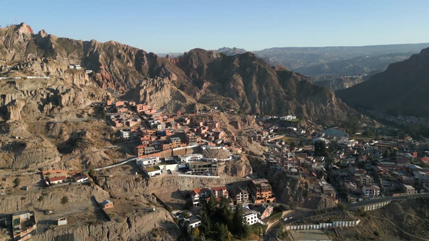 Aerial drone forward moving shot over La Paz City, Zona Sur District in Bolivia at sunrise. Andes mountain slope.
