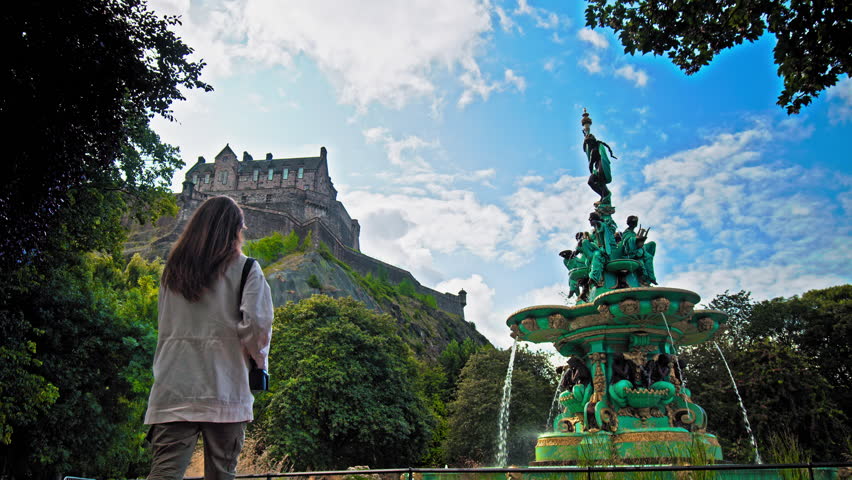 A beautiful woman visits Ross Fountain in Edinburgh, Scotland. Tourist girl looking at the Garden-side, cast-iron fountain representing science, arts, poetry and industry with Edinburgh Castle.
 Royalty-Free Stock Footage #1111264737