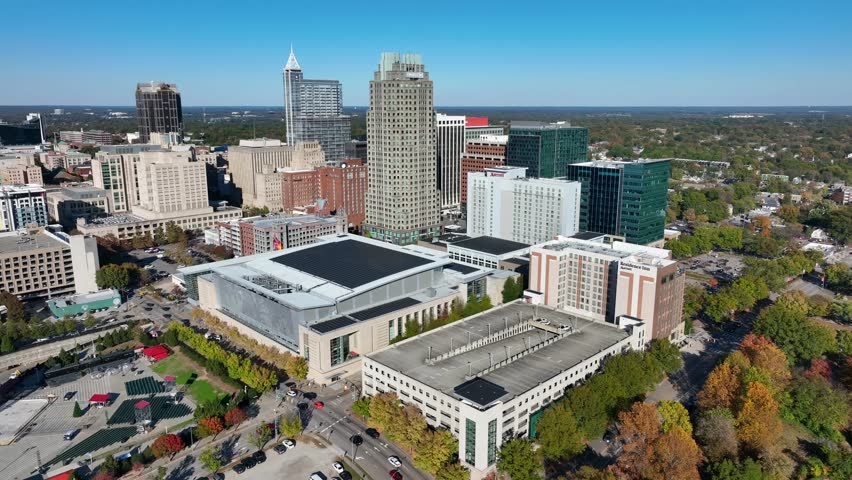 Raleigh, North Carolina skyline. Aerial orbit high above city on beautiful autumn day. Tall skyscrapers and Raleigh Convention Center.