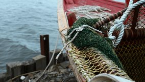 Close-up of fishing boat on wooden pier. Clip. Fishing nets on wooden boat standing on sea pier. Beautiful details of sea fishing boat on cloudy day
