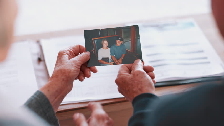 Photograph, memory and old couple in home remember date, event and marriage with nostalgia. Elderly people back, hands and photography as a reminder of life in vintage picture and thinking of history