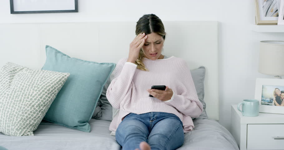 Cellphone, bed and woman sad, crying and depressed over bad news, social media announcement or email notification. Emotional crisis, smartphone and person worry, fail and reading info in home bedroom