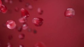  Super close-up of red juicy grains of pomegranate bouncing on the red background in slow motion. High quality FullHD footage
