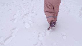 Close up video of 5 years old girl walking on a fenced sports ground. Fun winter holidays, enjoying winter day. Playing with snow in a beautiful snowfall. Holiday outdoors in cold winter