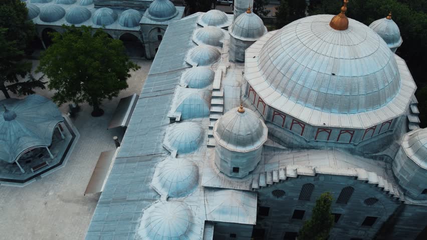 It is a camera movement flying towards the dome of a mosque. A few birds fly by and a bicycle passes below. Large and small domes are lined up. Royalty-Free Stock Footage #1111283937