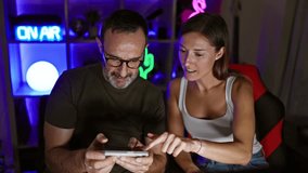 Two gamers, a father and daughter, happily learning the art of smartphone gaming while streaming from their home gaming room
