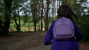 Girl with violet bag riding through the forest. 4k video footage in slow motion 