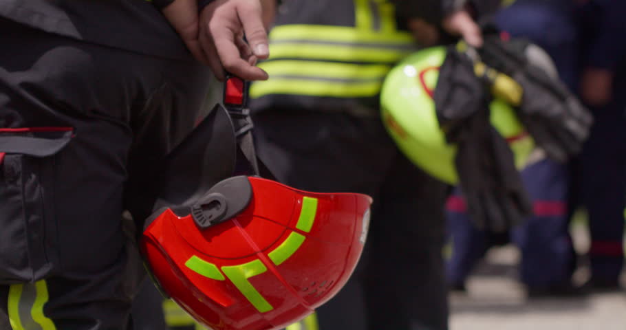 A close-up perspective focuses on a firefighter's hand as they hold a safety helmet, symbolizing their preparedness and dedication to ensuring their own safety and the safety of others during Royalty-Free Stock Footage #1111293039