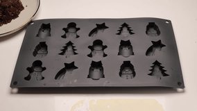 Fill chocolate into candy molds. Step-by-step preparation of chocolates for Christmas and New Year.  candies shaped like a Christmas tree, snowman, and stars.