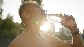 Close up older man drinking clear mineral water morning sun rays thirsty male drink pure aqua bottle city sunlight resting outside in park sport active sportsman healthy refreshing wellbeing energy - Powered by Shutterstock - Get 15% off with code: PIKWIZARD15