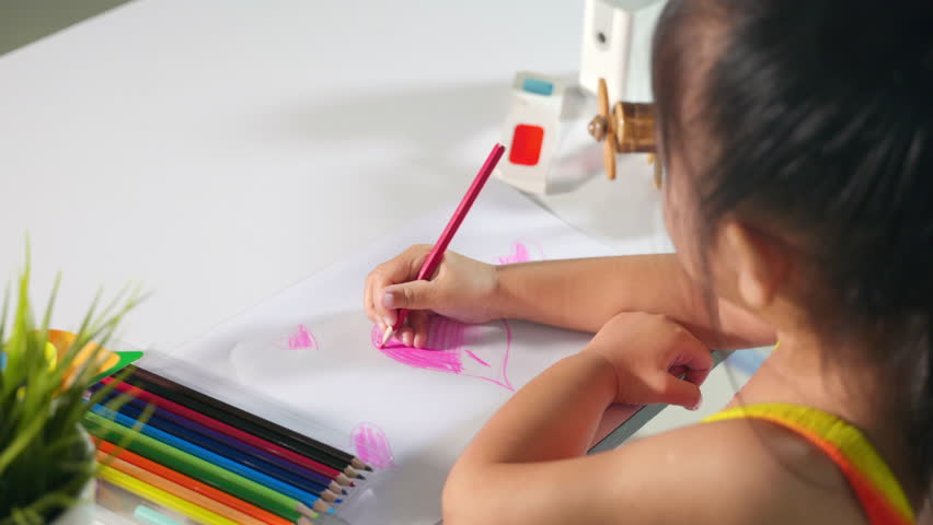 Happy child little girl colorful drawing pink heart on white paper, Asian cute kid preschooler smiling draw color love picture card at home, Valentine's or Mother's Day or Father's Day