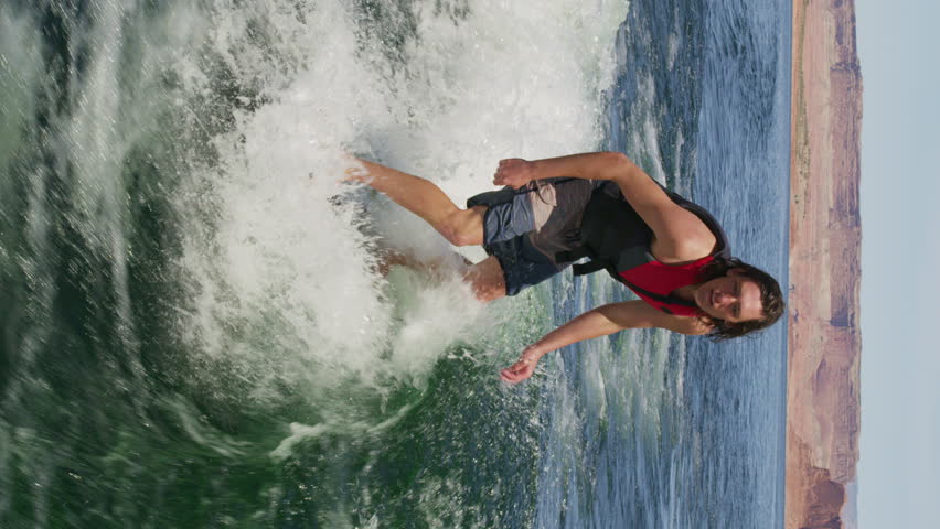 Medium slow motion high angle shot of wake surfer doing tricks - vertical video, lake powell, utah, united states Royalty-Free Stock Footage #1111299949