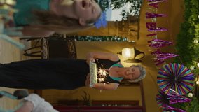 Woman carrying cake with sparklers to girls at birthday party - vertical video, cedar hills, utah, united states