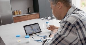 Senior biracial male patient and doctor having video call on tablet, slow motion. Telemedicine, healthcare, medical consultation, communication, domestic life and senior lifestyle, unaltered.