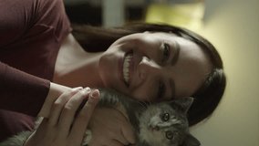 Portrait of smiling woman holding cat and looking at camera - vertical video, murray, utah, united states