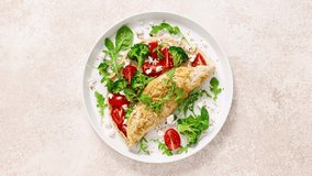 Omelette stuffed with tomato, broccoli, feta cheese and fresh green leaves of arugula and spinach. Healthy diet food, breakfast, stock video, footage 4k, top view