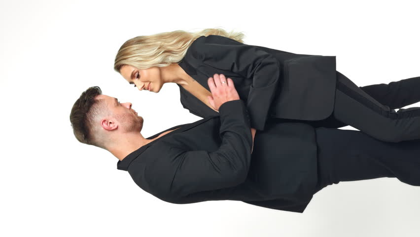 Sportive man caressing blonde woman. Caucasian couple kissing and stroking each other. Vertical screen. White backdrop. Royalty-Free Stock Footage #1111305437