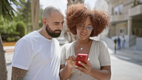 Beautiful couple, laughing and confidently standing together on a city street, smiling and bonding over shared messages on their smartphone - Powered by Shutterstock - Get 15% off with code: PIKWIZARD15