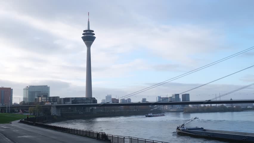 Cityscape of Dusseldorf over the Rhine river in winter day. Rheinturm tower and a bridge , cargo barges on the river Rhine , Nordrhein-Westfalen, Germany, Europe.