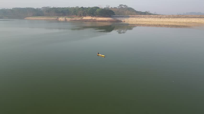 aerial view of a fishing boat is in the middle of a green lake in the morning