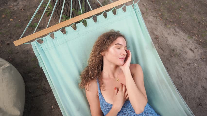 Сurly beautiful girl posing while lying on a hammock.