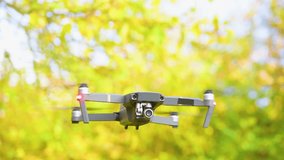 Drone  with digital camera and fast rotating propellers flying taking video and pictures. Greenery backgroud