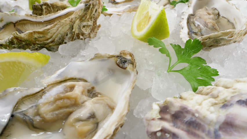Pacific oysters on ice with lemon. Raw edible seafood, close-up view | Shutterstock HD Video #1111334191