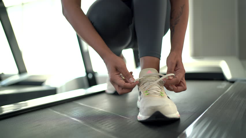 4K footage showing an unrecognizable active latino - hispanic young woman trying to tie shoelace in a fitness gym close up. Happy Sportswoman tie shoelaces and preparing herself for sport training. Royalty-Free Stock Footage #1111336185