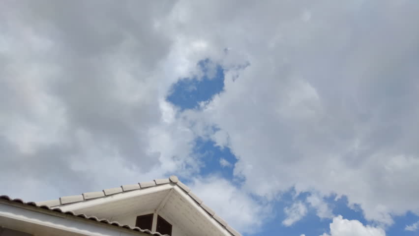 Time lapse clouds over the roof of house