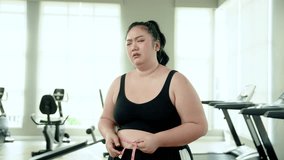 Chubby woman Exercise in fitness using a tape measure around waist. Face disappointed at not being able to lose weight to make waist smaller After running on the treadmill in attempt to lose weight - Powered by Shutterstock - Get 15% off with code: PIKWIZARD15