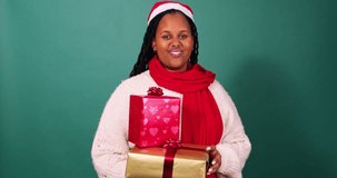 Beautiful young woman greets, waves hello and hands over wrapped Christmas gifts