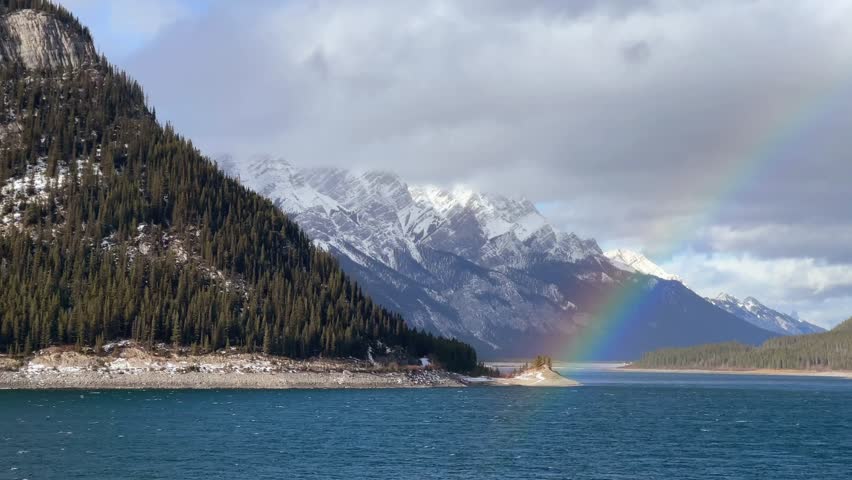 Rainbow over blue coloured lake in the mountains in Kananaskis, Canadian Rockies.